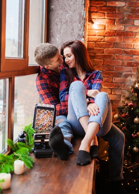 Der Typ und das Mädchen umarmen sich am Fenster. Ein verliebtes Paar freut sich an Silvester. Liebesgeschichte zum neuen Jahr