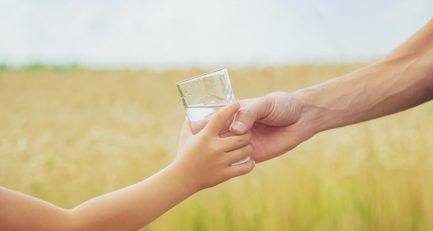 Der Vater gibt dem Kind Wasser im Hintergrund des Feldes