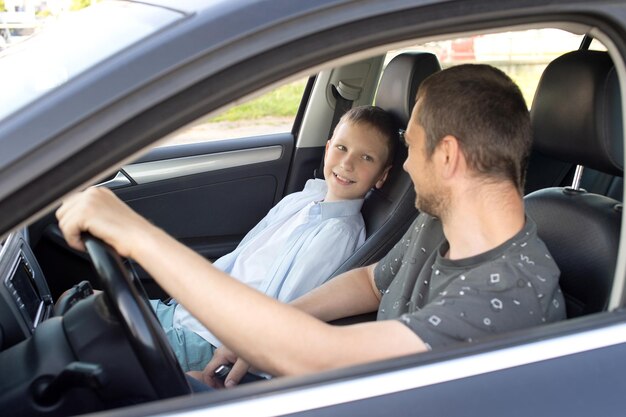 Der Vater sitzt mit dem Kind im Auto und hält das Lenkrad. Das Kind auf dem Vordersitz.