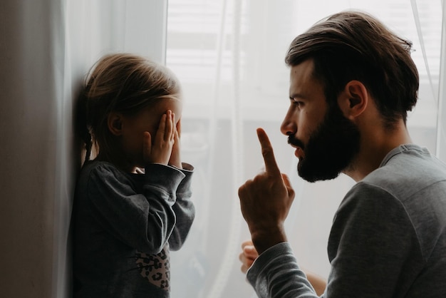 Der Vater stellt das Kind in eine Ecke und macht Bemerkungen über schlechtes Benehmen, indem er mit dem Zeigefinger in die Nähe seines Gesichts wedelt. Das Kind will keine Bestrafung und entschuldigt sich