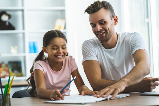 Der Vater und eine Tochter machen Hausaufgaben am Schreibtisch