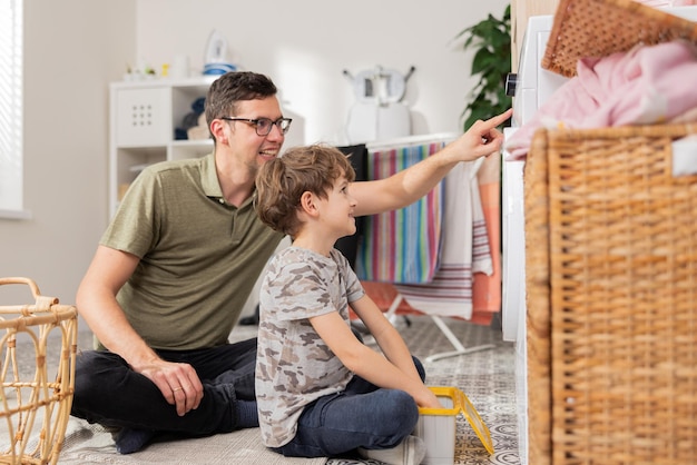 Der Vater verbringt Zeit mit kleinen Kindern in der Waschküche. Das Badezimmer erledigt während des Mutterschaftsurlaubs Haushaltsarbeiten. Er kümmert sich um den Sohn. Er zeigt dem Jungen, wie man eine Waschmaschine bedient