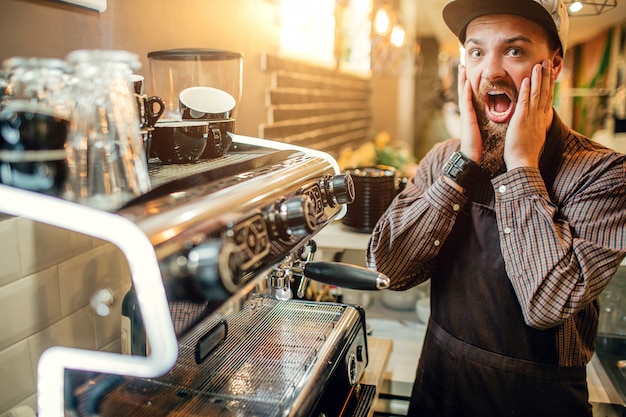 Der verängstigte junge Barista schaut vor die Kamera.