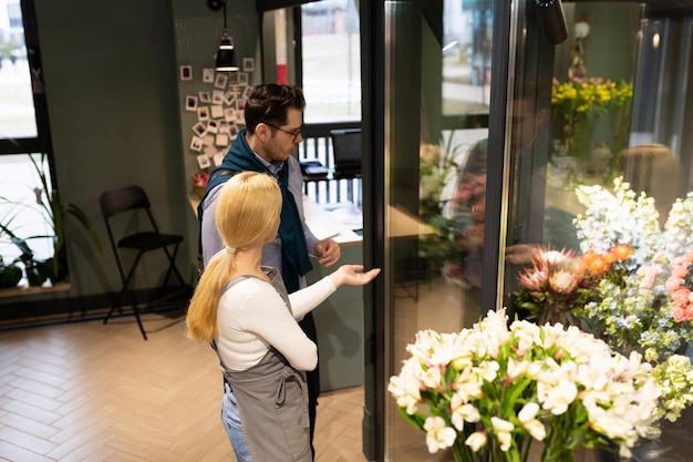 Der Verkäufer und der Käufer im Blumenladen werden mit einem Blumenset für den Blumenstrauß bestimmt