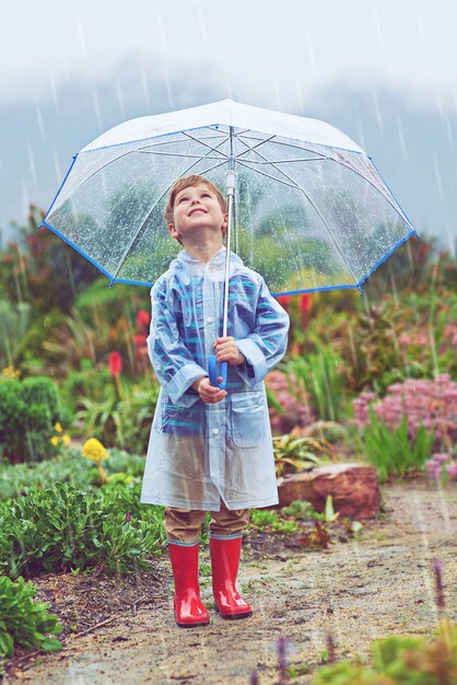 Der Versuch, die Quelle des Regens zu finden Ganzkörperaufnahme eines Jungen, der draußen im Regen steht