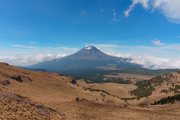 Der Vulkan Popocatepetl mit einem felsigen Hügel im Vordergrund