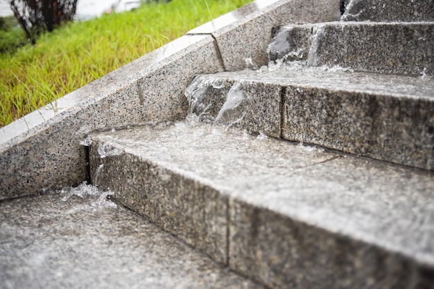 Der Wasserstrahl fließt von den Stufen der Treppe herunter. Starkregen. Regnerisches Herbstwetter.