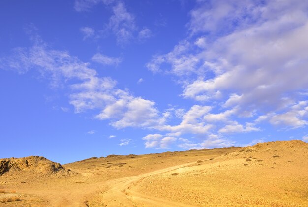 Der Weg zum blauen Himmel Ein felsiger Hang in der Kurai-Steppe im Frühling bei bewölktem Himmel