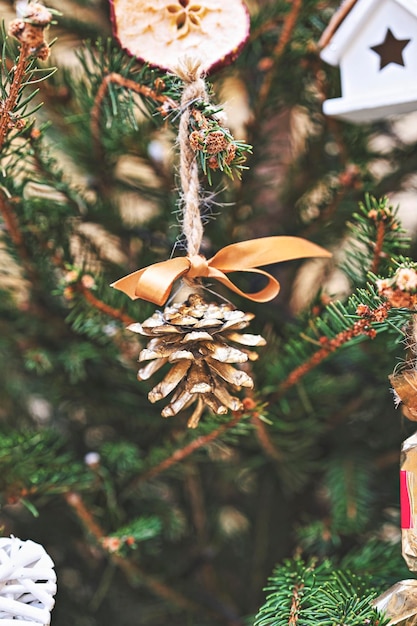 Der Weihnachtsbaum ist mit einem goldfarbenen Tannenzapfen geschmückt. Handgemachte Weihnachtsdekorationen ohne Abfall und ohne Plastik