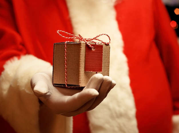 Der Weihnachtsmann behandschuhte Hände, die Geschenkbox halten