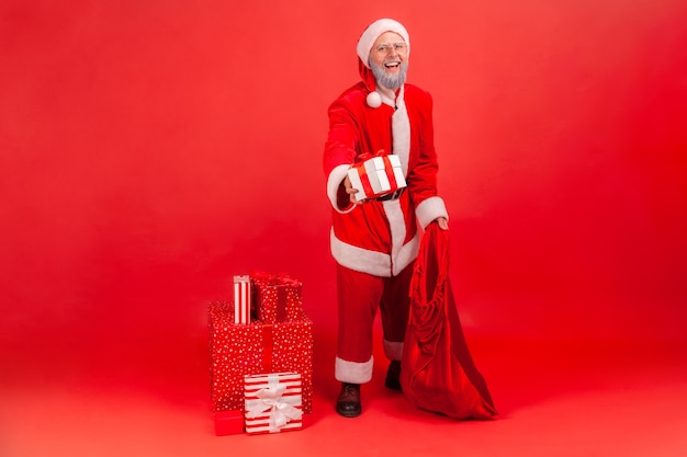 Der Weihnachtsmann, der Tasche mit Geschenken hält und Geschenkbox gibt, gratuliert zu den Winterferien.