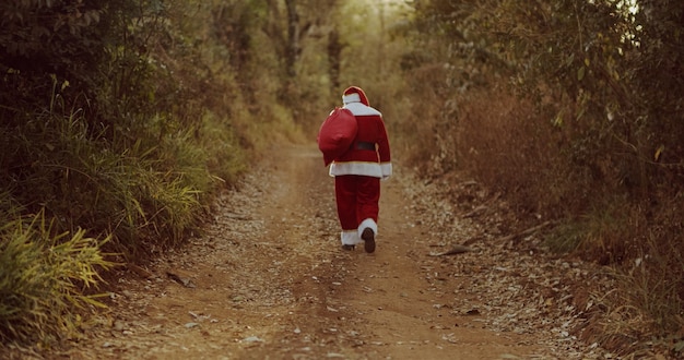 Der Weihnachtsmann geht einen Feldweg entlang und sucht nach einer Adresse auf dem Bauernhof