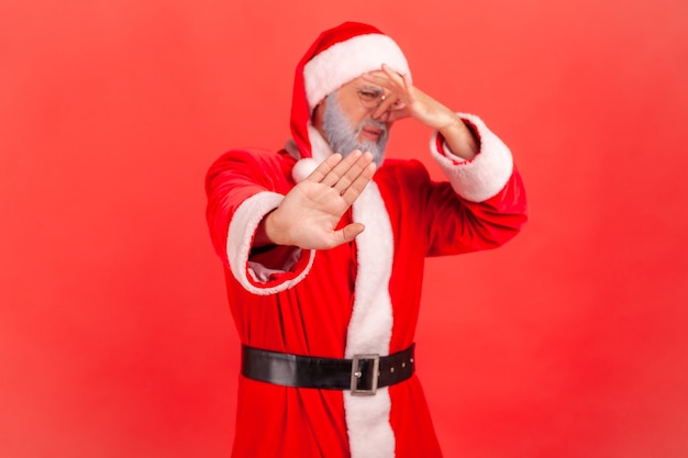 Der Weihnachtsmann kneift mit den Fingern in die Nase, um schlechten Geruch zu vermeiden und zeigt Stoppgeste