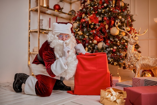 Der Weihnachtsmann mit einer großen roten Tüte mit Geschenken eilt herbei, um den Kindern ein Geschenk zu bringen. Neues Jahr und Frohe Weihnachten, Frohe Feiertage Konzept