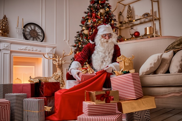 Der Weihnachtsmann packt Geschenke in seine große rote Tasche, um den Kindern ein frohes Weihnachtsfest zu wünschen.