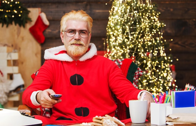 Der Weihnachtsmann sitzt im Sessel und sieht sich den Weihnachtsfilm an, der das ferngesteuerte Neujahrskino hält