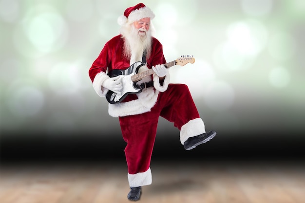 Der Weihnachtsmann vergnügt sich mit einer Gitarre vor schimmernder Lichtgestaltung über Brettern