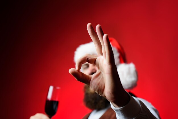 Der Weihnachtsmann zeigt vor der Kamera ein Zeichen in Ordnung. Bärtiger Mann zeigt Zeichen in Ordnung an der Kamera. Lächelnder Mann im Sankt-Kostüm. Weihnachtsförderungskonzept. Verkauf. Rabatt. Selektiver Fokus. Unterschrift. Unterschreiben in Ordnung.