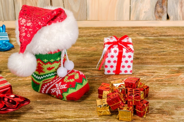 Der Weihnachtsstrumpf mit der Weihnachtsmütze ist auf einem zerkratzten Holztisch. In der Nähe liegen dekorative Süßigkeiten.