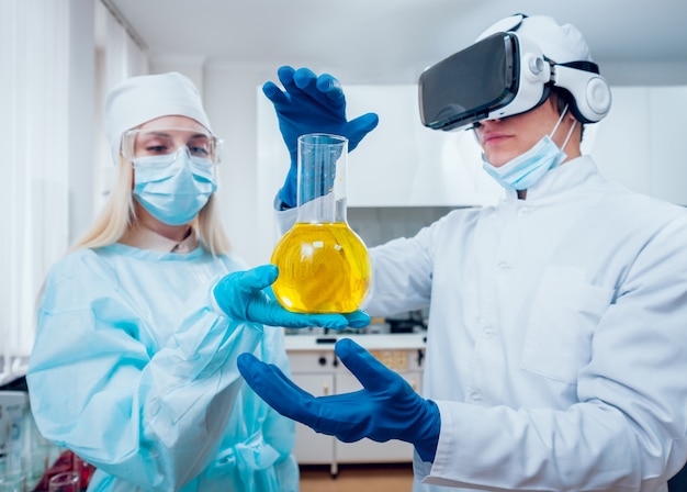 Der Wissenschaftstechniker in Virtual-Reality-Brillen untersucht das Medikament im Labor.