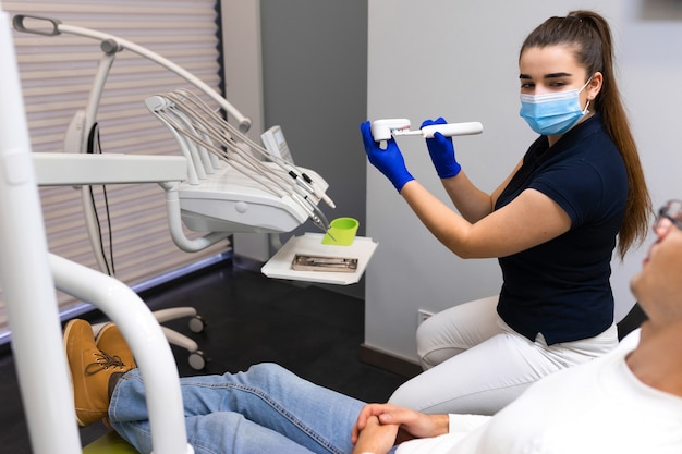 Der Zahnarzt bringt dem Patienten bei, wie man Zähne putzt.