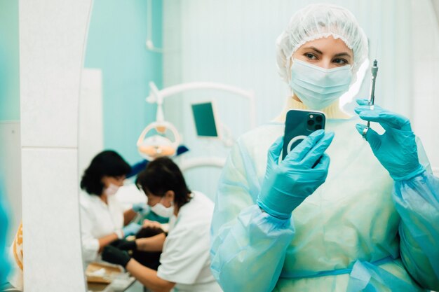 Der Zahnarzt in einer Schutzmaske steht neben dem Patienten und macht nach der Arbeit ein Foto