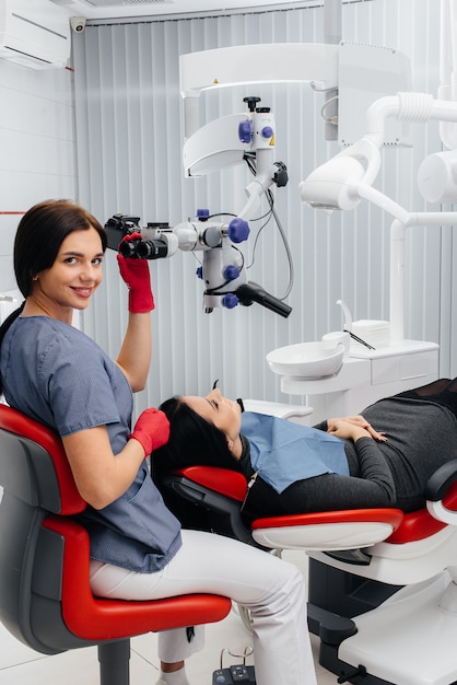 Der Zahnarzt schaut durch ein Mikroskop und operiert den Patienten.