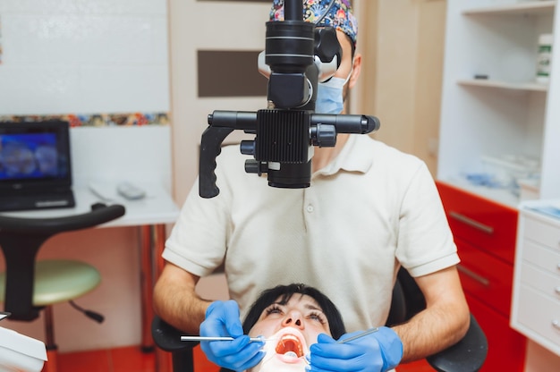 Der Zahnarzt untersucht den Mund des Patienten mit einem Zahnmikroskop Zahnbehandlung das Konzept des Mikroskops für gesunde Zähne in der Zahnmedizin