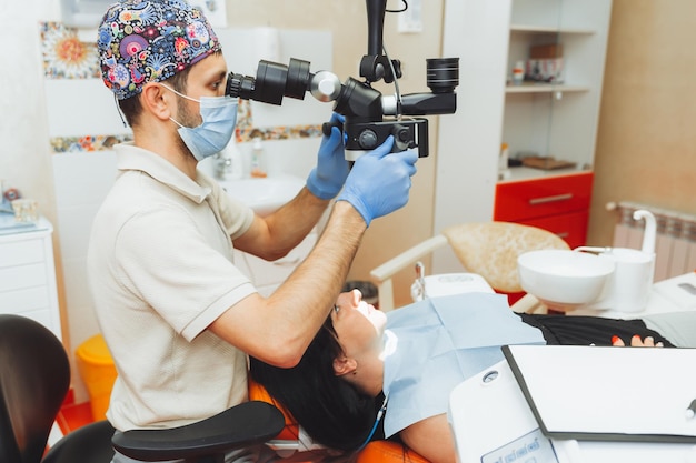 Der Zahnarzt untersucht den Mund des Patienten mit einem Zahnmikroskop Zahnbehandlung das Konzept des Mikroskops für gesunde Zähne in der Zahnmedizin