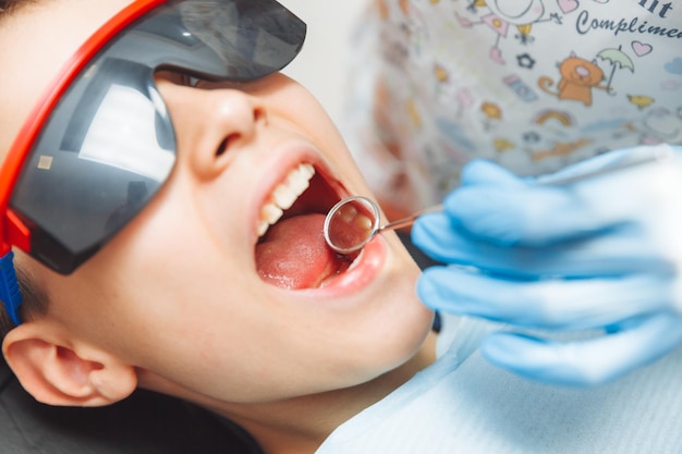 Der Zahnarzt untersucht die Zähne eines 13-jährigen Jungen in der Klinik für Kinderzahnheilkunde