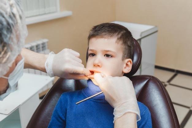 Der Zahnarzt untersucht die Zähne eines kleinen Jungen, eines Patienten in einer Zahnklinik