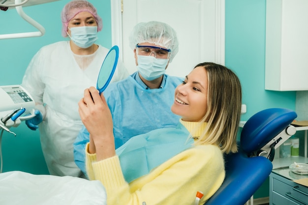 Der Zahnarzt zeigt dem Klienten die Ergebnisse seiner Arbeit im Spiegel