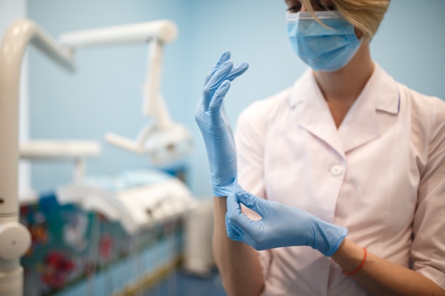 Der Zahnarzt zieht vor der Operation Handschuhe an. Nahansicht