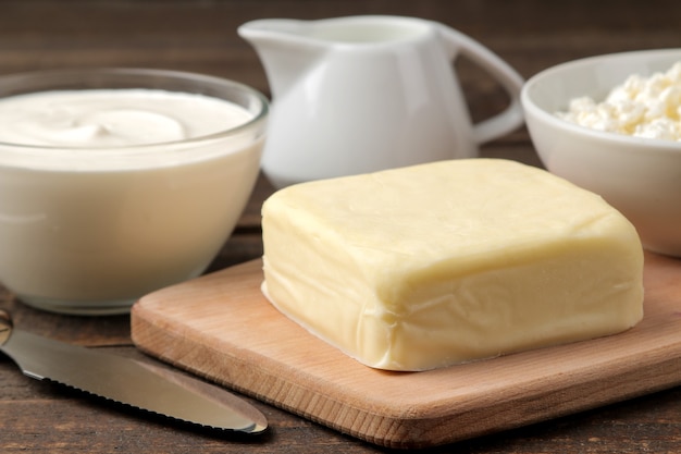 Derivados do leite. leite, creme de leite, queijo, manteiga e queijo cottage em uma mesa de madeira marrom