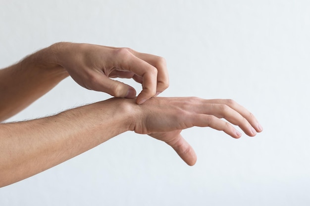 Dermatite, eczema, alergia, conceito de psoríase. homem coçando coceira no braço, fundo de estúdio cinza. homem com coceira no cotovelo, copie o espaço