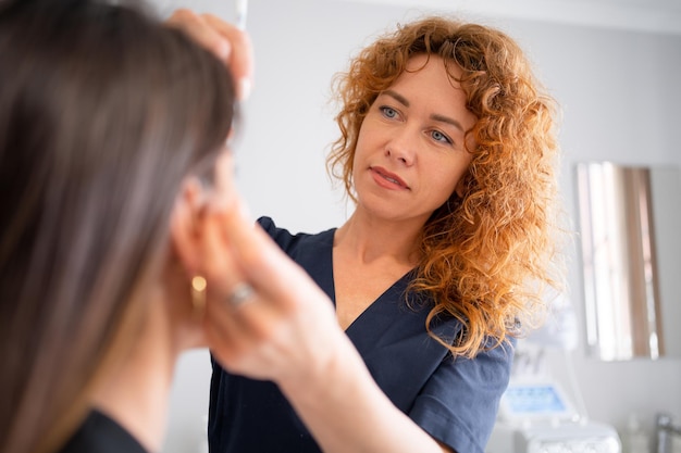 Foto dermatologe führt eine behandlung bei einer kundenin in einer klinik durch