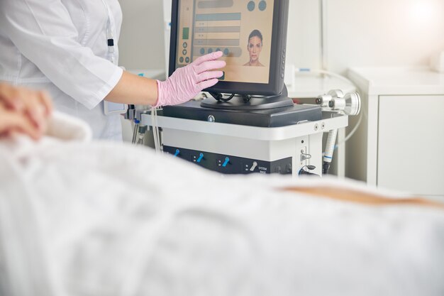 Dermatologista ajustando os parâmetros de tratamento para sua cliente antes do procedimento de dermoabrasão