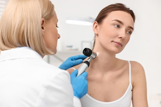 Dermatologista com dermatoscópio examinando paciente na clínica