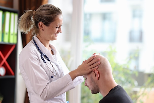 Dermatologista positivo examina cabeça careca de jovem em paciente de consultório médico com alopecia