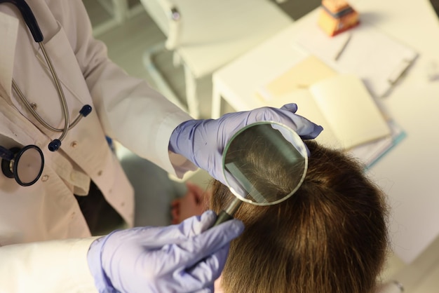 El dermatólogo examina la piel y el cabello de una paciente con lupa en una clínica médica