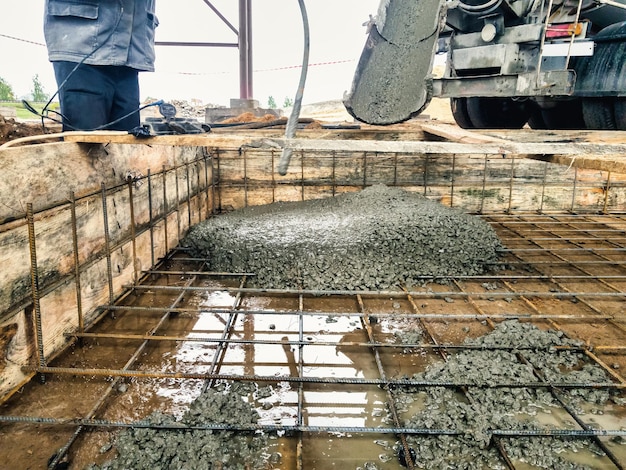 Derramando a fundação com concreto no canteiro de obras Trabalhos monolíticos de concreto armado durante a construção do edifício