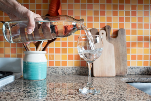 derramando água em copo na cozinha