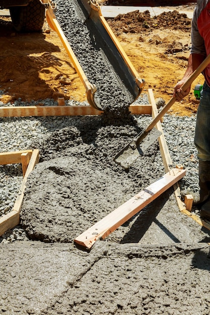 Derramando cimento durante a atualização para pavimento de concreto de pavimentação de rua residencial perto da casa