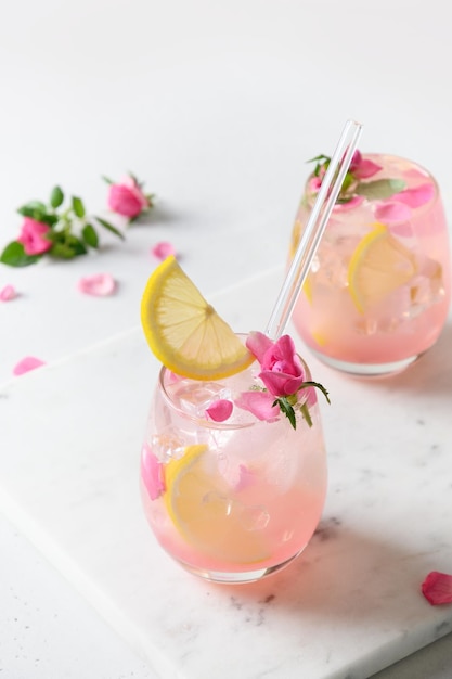 Derramando coquetel alcoólico rosa com flores rosas em fundo branco