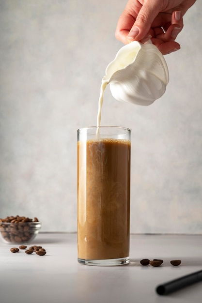 Derramando leite em copo com café gelado Refresco frio bebida doce de verão