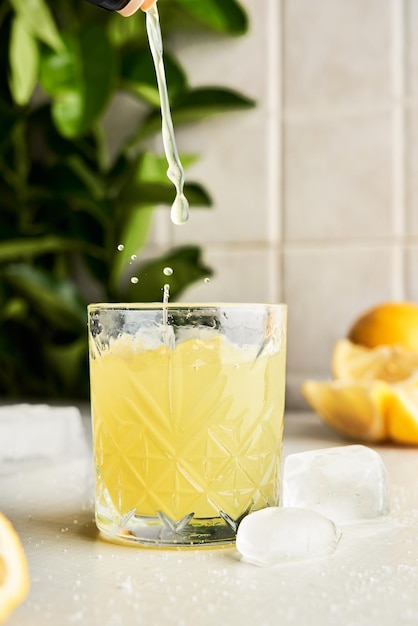 Derramando limoncello digestivo típico italiano em um copo com fundo de cozinha