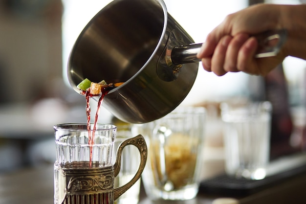 Derramando vinho quente em um copo de metal