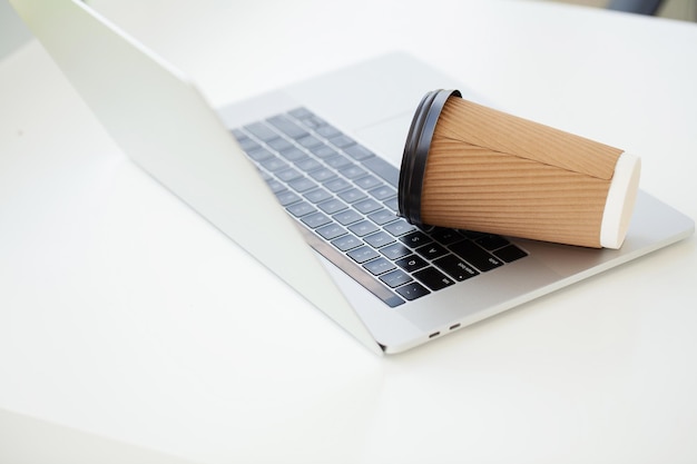 Derrame café del vaso de papel en el teclado de la computadora portátil