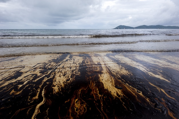 Derrame de petróleo mezclado con otras sustancias químicas en la superficie del mar y arena.