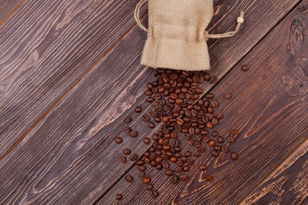 Derramó los granos de café del saco. Superficie de madera rústica vieja. Vista superior desde arriba.